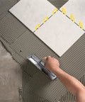 Installed view of yellow 3/16 inch horseshoe plastic tile shims used for leveling between ceramic tiles.