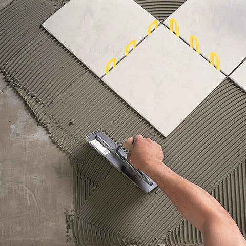 Installed view of yellow 3/16 inch horseshoe plastic tile shims used for leveling between ceramic tiles.