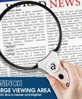 3X Lighted Magnifying Glass With LED And UV Light, 5.5 Inch Handheld Magnifier for reading, held over newspaper text