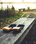 Square Cast Iron Pie Iron Sandwich Cooker For Campfire Cooking And Backyard BBQ on rustic wood bench with sandwiches