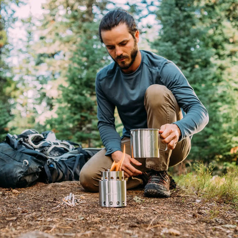 Camper setting up Ultra Lightweight Wood Burning Stove Kit For Backpacking And Camping With Backup Alcohol Burner Survival Ready