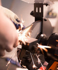 Person using the Rock Hard Bench Grinder with Eight Inch Grinding Wheels and a snappy variable speed motor, producing sparks while sharpening metal.