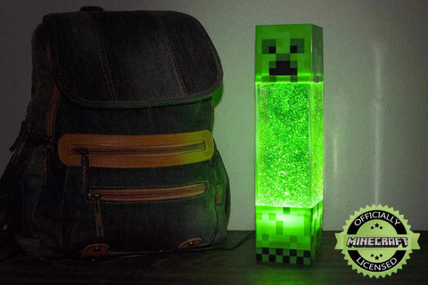 Glitter Creeper Mood Light 12 Inch LED Lamp for Gaming Rooms and Kids Rooms Minecraft Themed Neon Glitter Night Light Battery or USB Powered with 15 Minute Auto Shutoff Fun Desk Decor and Glow Gift next to a backpack