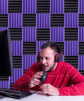 Person using a microphone in front of a wall made of No Nonsense Heavy Duty 2X12 Acoustic Foam Squares And Soundproofing Bricks.