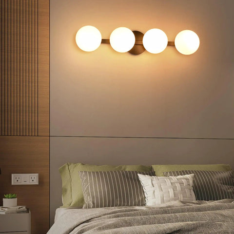 Sleek Matte Black Four Light Vanity Light Fixture With Opal Glass Globes above a bed, offering modern wall sconce lighting for bathrooms and mirrors
