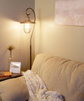 58 Inch Industrial Nautical Floor Lamp With Hanging Cage Shade, Brushed Pewter Finish in living room corner beside sofa