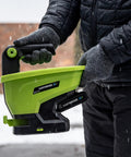 Person holding 20-Volt Cordless Handheld Seed And Fertilizer Spreader For Yard Work With Adjustable Spreading Rate Dial