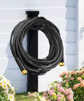 Garden hose, Haeteir 50ft non-expanding, black fabric exterior with brass fittings mounted on outdoor wall.