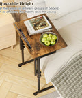 Adjustable Folding TV Tray Table For Eating And Snacking next to bed with book and fruit, brown MDF top, 6 height levels, C shaped legs
