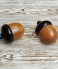 Hella Slick Screw Open Miniature Black Ebony Acorn Curios Set Of Two With Hidden Antique Bronze Pinecones showcasing wooden acorns on a rustic backdrop.
