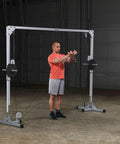 Man using Beefy Heavy Duty Cable Crossover Machine For Home Gym Functional Trainer with dual pulleys in gym setting.
