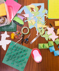 Craft table with papers and colored Heavy Duty 3 Inch Circle Punch With Spring Action Lever Built Tough Durable Steel Blade for scrapbooking.