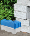Plastic mold for creating hollow bricks next to stacked concrete blocks, featuring Hollow Brick Molds For Concrete Reusable Plastic Paver Mold For DIY Garden Walls And Patio Decor Rugged Concrete Forms For Outdoor Pathways And Landscaping.