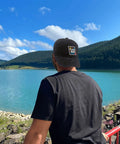 Stay Cool With This Breathable Yacht Style Hat For Men And Women Unisex Cap All Season Lightweight Moisture Wicking Adjustable Fit Perfect For Running Hiking Cycling And Everyday Outdoor Wear Go To Pick For Everyday Adventures viewed from behind by a lake with mountains.
