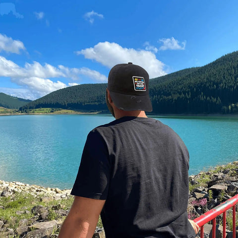 Stay Cool With This Breathable Yacht Style Hat For Men And Women Unisex Cap All Season Lightweight Moisture Wicking Adjustable Fit Perfect For Running Hiking Cycling And Everyday Outdoor Wear Go To Pick For Everyday Adventures viewed from behind by a lake with mountains.