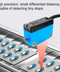 Compact Diffuse Photoelectric Sensor With Background Suppression And 2mm Red Laser, No Fuss Install, Sensing Range 20 To 300 Mm, 10 To 30 VDC, PNP Output, Unaffected By Background Color, Ideal For Transparent Objects, shown over blister packs