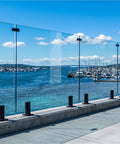 Heavy Duty Six Panel Frameless Tempered Glass Deck Railing Kit With Complete 2205 Stainless Steel Mounting Hardware overlooking a marina.