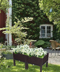 Plastic Square Raised Garden Bed Set With Self-Watering Design For Indoor And Outdoor Use, No-Fuss For Growing Vegetables, Fruits, Potatoes And Flowers, Flexible Modular System, All Weather Durability, 2 Piece Kit placed in a garden filled with blooming flowers.