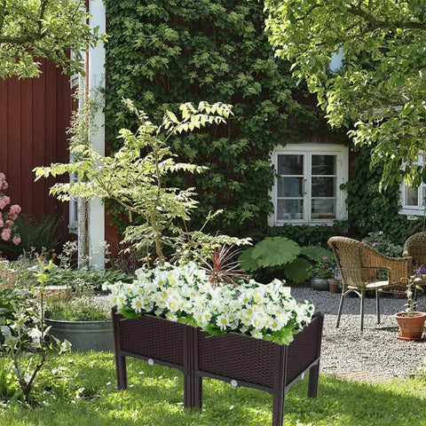Plastic Square Raised Garden Bed Set With Self-Watering Design For Indoor And Outdoor Use, No-Fuss For Growing Vegetables, Fruits, Potatoes And Flowers, Flexible Modular System, All Weather Durability, 2 Piece Kit placed in a garden filled with blooming flowers.