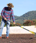Man using 19 Tine Cold Pressed Steel Dethatcher Rake With 72 Inch Adjustable Handle And Ergonomic Grip for lawn care.