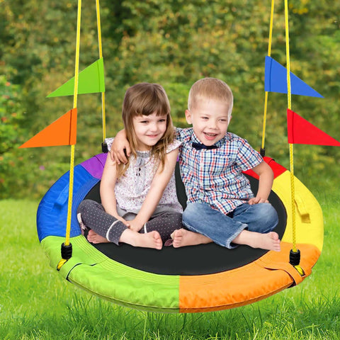 Two children sitting on Heavy Duty 750Lb Saucer Tree Swing With Adjustable Straps, colorful design, in outdoor backyard setting.