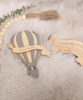 Wooden Hot Air Balloon Monthly Milestone Cards For Babies, My First Year Sign set on fluffy surface with greenery.