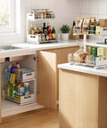 Sleek Two Tier Pull Out Under Sink Organizer For Kitchen Cabinets with cleaning supplies under sink and pantry items on counter.