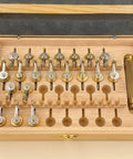 Open wooden box displaying Pro Grade 20 Calibers Watch Mainspring Winder Kit with barrels and copper tools for horology repairs.