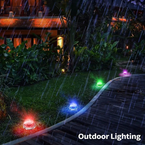 Sun Powered Solar Ground Lights 12 Pack With 8 LED In-Ground Disk Lights illuminating a pathway in the rain, multicolor glow.