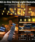 Outdoor Solar String Lights 50 Feet ST38 Shatterproof Bulbs Copper Wire Waterproof Patio Garden Lighting USB Charging Remote Control With 3 Modes Dimmable Solar Light No Outlet Needed For Camping Backyard And Patio Ambiance shown with remote control against a lit outdoor patio.