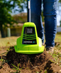 Green 20V Cordless Garden Tiller Cultivator with 7.5 Inch Tilling Head in use on garden soil