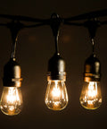 Close-up of Beefed-Up 100 Foot Outdoor Commercial String Lights with E26 suspended sockets, three glowing S14 11W bulbs.