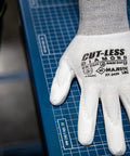 Cut-Less Dyneema Gloves With Polyurethane Palm, 1 Dozen LG, 13 Gauge Liner, ANSI A3, shown on a blue grid surface.
