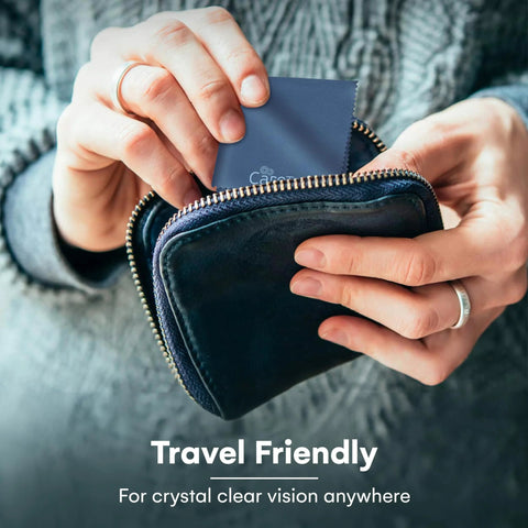 Front view of hands pulling a navy blue Care Touch microfiber cleaning cloth from a small zippered pouch.
