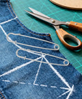 Get Your Duds Locked Down With These 50 Heavy Duty Iron Safety Pins, Retro Silver Brooch Clips For Jackets And Cardigans, Perfect For Outdoor Adventures And Industrial Grind Without Any Drama Or Failures - two silver safety pins on denim fabric with scissors