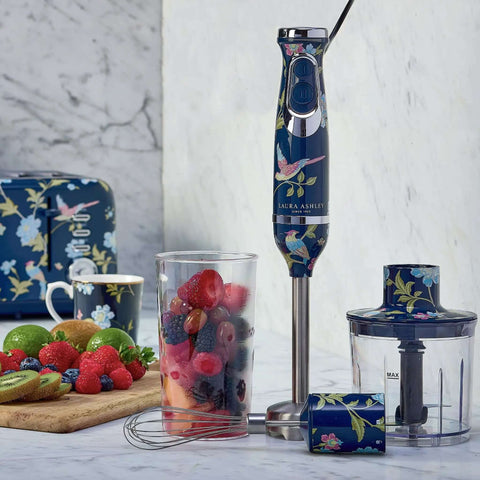 Top Shelf Handheld Immersion Blender Offering Two Variable Speed Options For Heavy Duty Blending And Fast Chopping Slick Electric Hand Mixer Kitchen Workhorse Elite with fruits in glass.