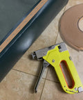 Rock Solid 33 Yards Upholstery Tack Strips For Couch Furniture Edge Fixation with staple gun and roll on a tiled surface.