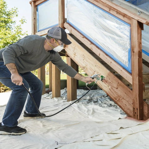 Man using Professional HEA Airless Paint Sprayer That Slashes Overspray And Delivers A Hella Smooth Finish on deck stairs.