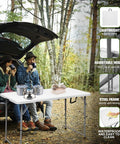 Sturdy 4 Foot Portable Folding Table That Folds In Half, set up near a car in a forest, used for outdoor camping with people.