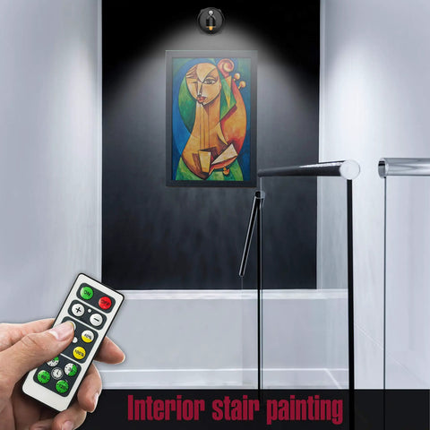 Two Pack Cordless LED Spotlight With Rotatable Heads for Indoor Art Paintings illuminating framed artwork above stairs