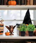 Two Pack Mini Faux Plants In Black Pots For Home Or Office Desk Decor Indoor Low Maintenance No Water Needed Realistic Artificial Plants for Bathrooms Living Rooms And Workspaces displayed on a shelf with Halloween decor.