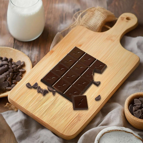 Bamboo cutting board with handle, 11x5 inches, wood grain, topped with chocolate chunks for serving
