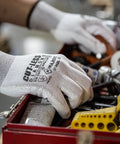 Person wearing Cut-Less Dyneema Gloves With Polyurethane Palm, 1 Dozen LG, handling tools in a workshop.