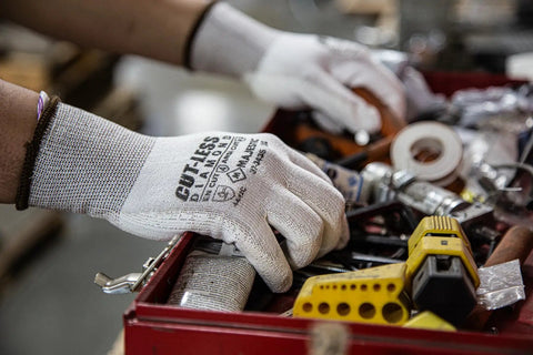 Person wearing Cut-Less Dyneema Gloves With Polyurethane Palm, 1 Dozen LG, handling tools in a workshop.