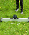 Heavy Duty 24 Inch Rolling Magnetic Pickup Sweeper With Adjustable Handle scraping grass to collect nails and metal debris.