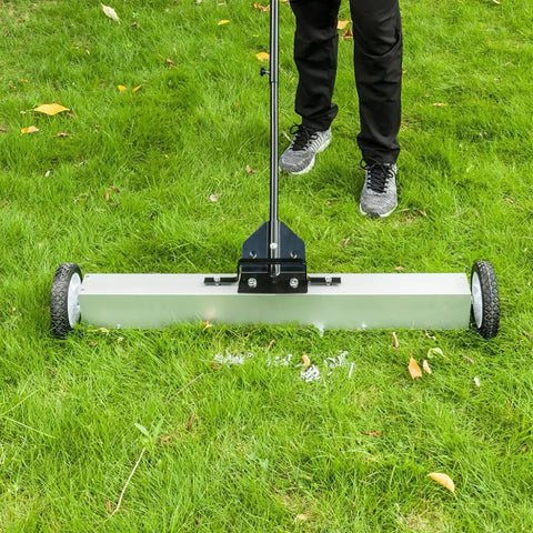 Heavy Duty 24 Inch Rolling Magnetic Pickup Sweeper With Adjustable Handle scraping grass to collect nails and metal debris.