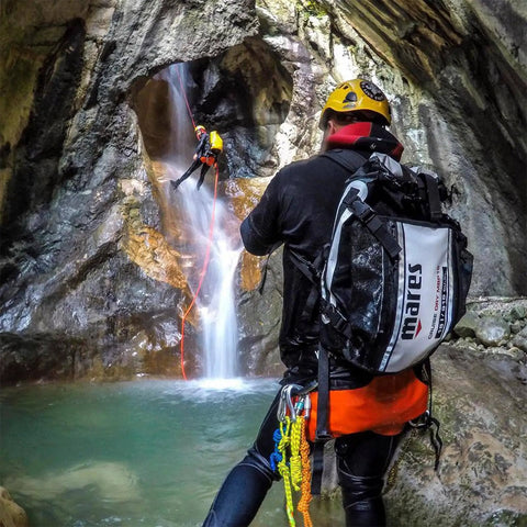 Canyon with person rappelling beside waterfall, carrying Cruise Dry MBP15 15 Liter Dive Gear Bag Roll Top Waterproof Dry Sack.
