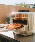 Person using Stainless Pizza Peel With Built In Ridges Serving Board And Pizza Paddle For Ovens 304 Stainless Steel 24 In Long By 11.75 In Wide Lightweight 1.8 Lbs Game Changer For Easy Home Pizza Nights to take pizza from oven