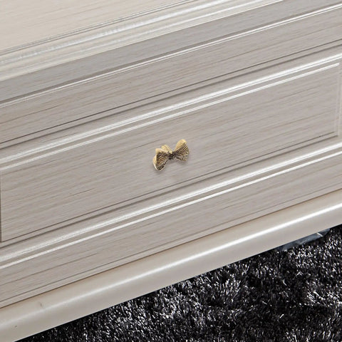 Copper Bowknot Cabinet Handle And Drawer Pull Kit In Vintage Brass Finish on white dresser drawer