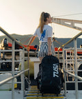 Person on dock with Roller Mesh Dive Gear Bag With Large Outer Pocket And Internal Pocket, Adjustable Shoulder Strap, Top And Side Handles